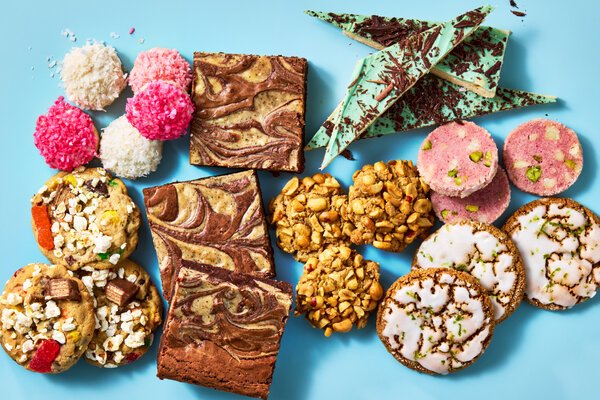 An overhead image of vibrant holiday cookies against a two-toned blue background
