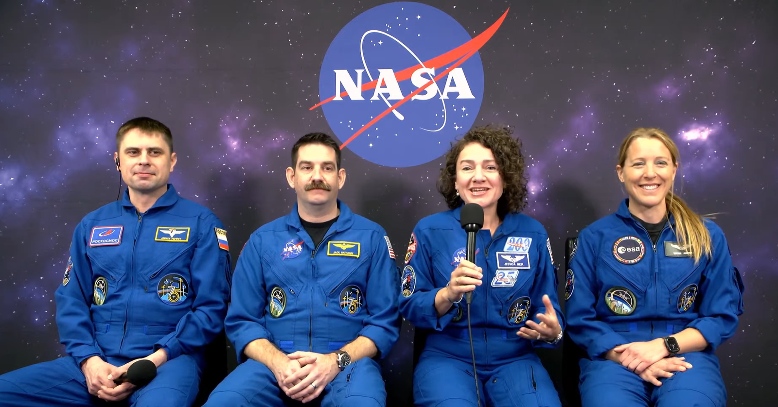 Image shows a NASA insignia in the background while four astronauts in blue flight suits sit and speak virtually to the media inside Astronaut Crew Quarters at NASA's Kennedy Space Center in Florida on Sunday, Feb. 8, 2026. Photo credit: NASA