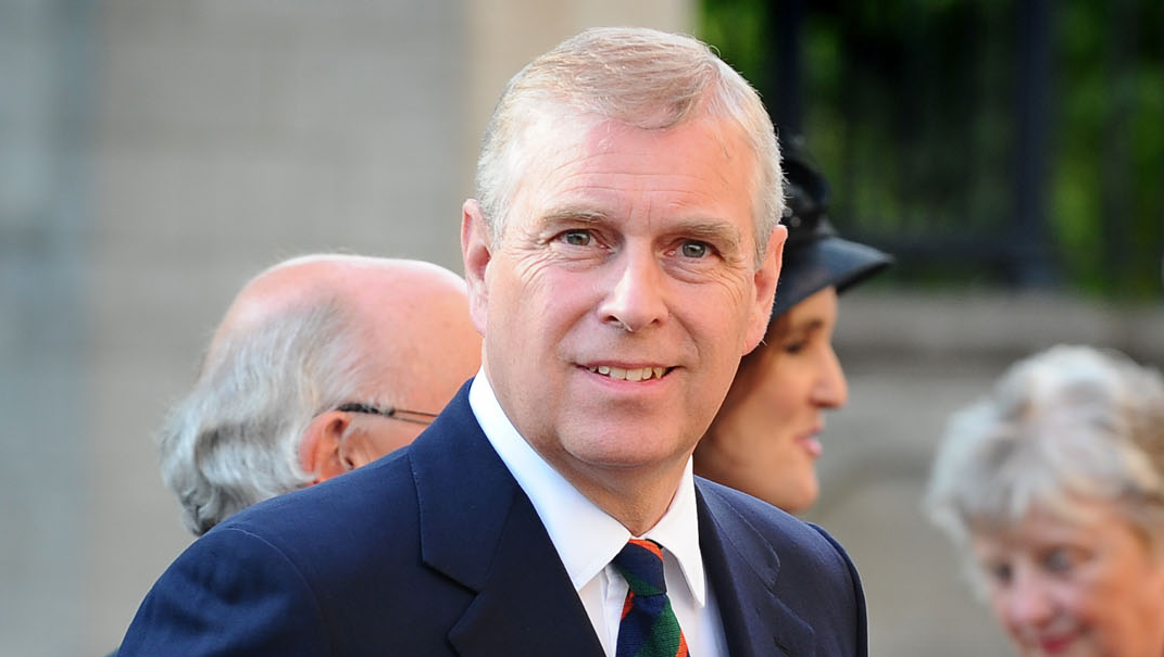 Prince Andrew smiles as he walks along past a crowd