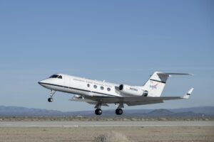 An aircraft lifts off from a runway into a blue sky.