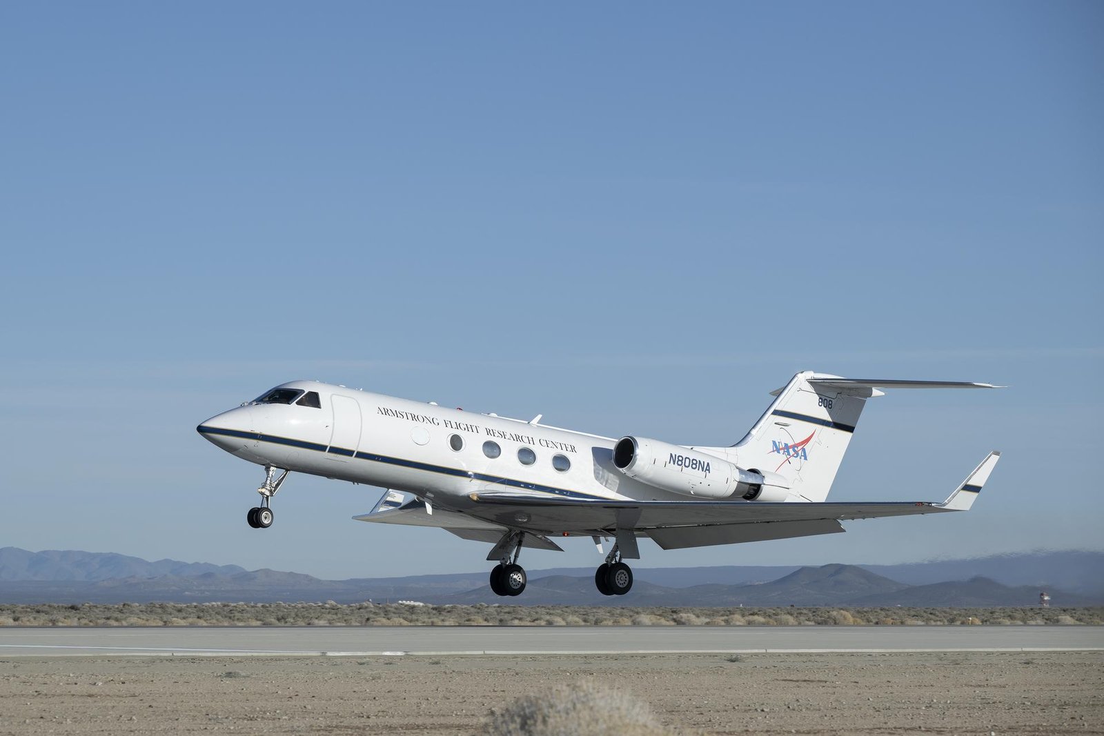 An aircraft lifts off from a runway into a blue sky.