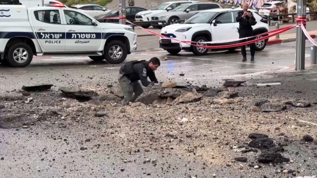 Israeli police inspect damage on the road after missile impact | US-Israel war on Iran