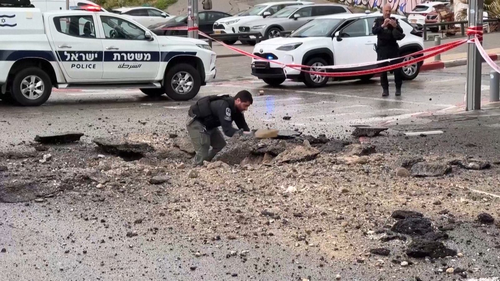 Israeli police inspect damage on the road after missile impact | US-Israel war on Iran