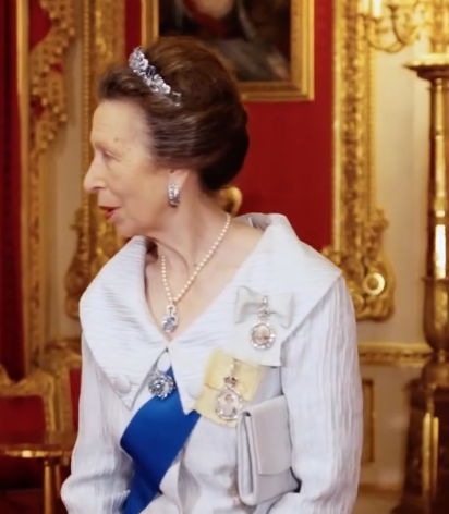 Princess Anne wears a white dress with a large collar effect and an aquamarine and diamond tiara