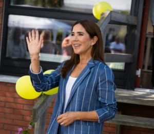 Queen Mary of Denmark waves as she arrives to open a counselling centre. She is wearing a blue suit with white stripes.