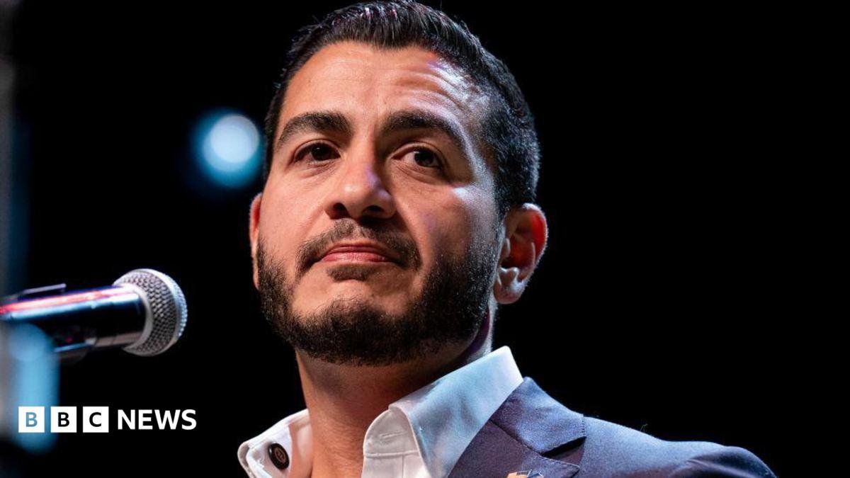 Abdul El-Sayed on stage wearing an open necked white shirt and blue suit jacked, at an election night watch party at The Majestic Theatre in Detroit