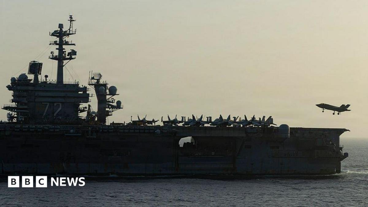 Side view of USS Abraham Lincoln as a small jet lands on it