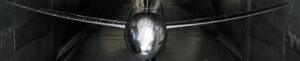 A metallic CRM aircraft model with swept wings is positioned inside a dark wind tunnel.