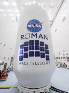Close-up view of the Roman Space Telescope’s payload, wrapped in white covering with the NASA logo and Roman Space Telescope insignia displayed prominently.